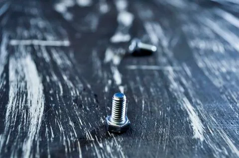 Nuts for repairs lying on a wooden table. Iron nuts and screws f Stock Photos