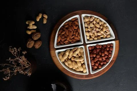 Nuts sprinkled in plates, hazelnuts, almonds, pistachios, peanuts Stock Photos