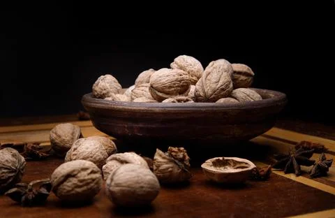 Nuts. Walnut kernels and whole walnuts on a dark wooden table. Black background Stock Photos