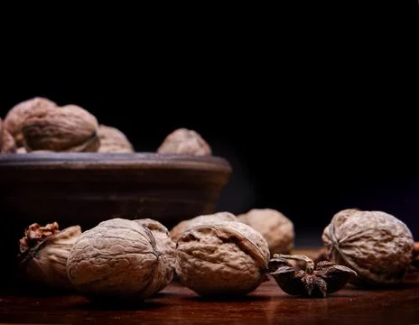 Nuts. Walnut kernels and whole walnuts on a dark wooden table. Black background Stock Photos