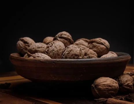Nuts. Walnut kernels and whole walnuts on a dark wooden table. Black background Stock Photos