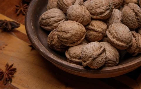 Nuts. whole walnuts in an earthenware dish on a dark wooden table. Stock Photos
