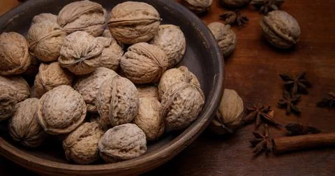 Nuts. whole walnuts in an earthenware dish on a dark wooden table. Stock Photos