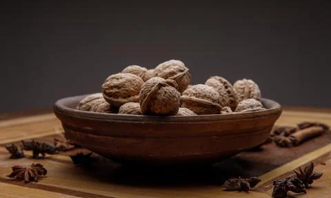 Nuts. whole walnuts in an earthenware dish on a dark wooden table. Stock Photos