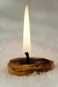 Nutshell with burning candle laying in snow Stock Photos