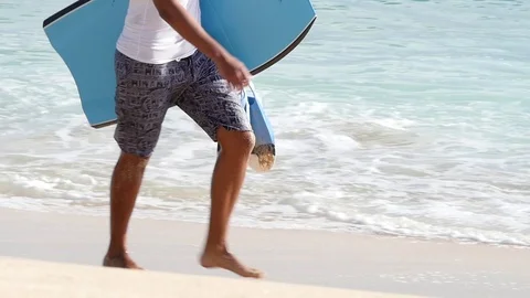 OAHU HAWAII - SEPT 5, 2016 Slow Motion Man walking with boogie board on beach Stock Footage 74642396