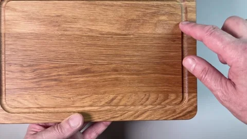 Oak cutting board with groove in hands on gray background Stock Footage 342276773