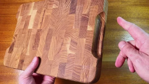 Oak end grain cutting board in hands above the table Stock Footage 342276533