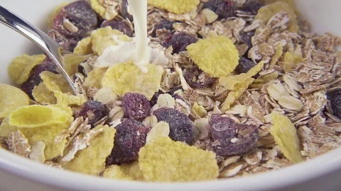 In oat and corn flakes with dried fruits pour milk slow motion Stock Footage 92377018