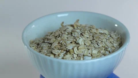 Oat flakes are poured into a white plate. Stock Footage 295212591