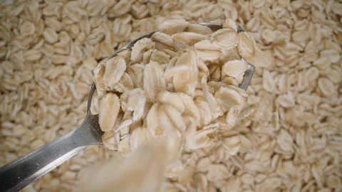 Oat flakes falling from above onto a spoon, a healthy breakfast, top view, backg Stock Footage 265734013