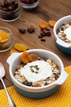 Oat flakes with nuts, dried fruit mix in bowl over rustic wooden table, isola Stock Photos