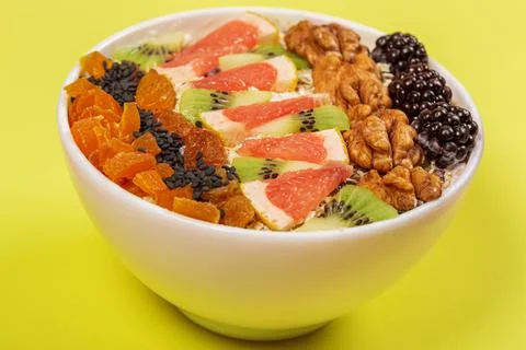 Oat flakes with walnuts and fruit pieces on yellow background Stock Photos
