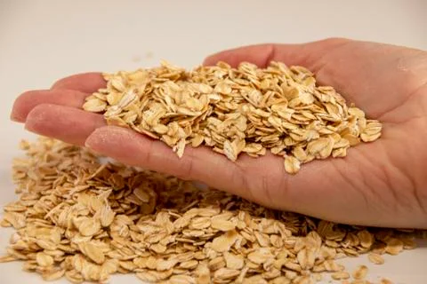 Oat grain in the palms on a white background, side view Stockfoto's