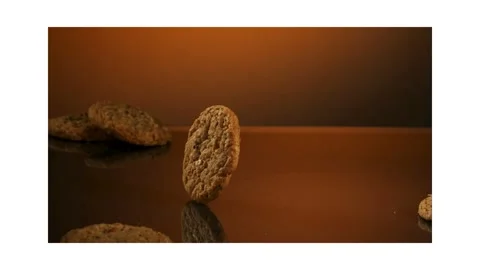 Oatmeal cookie rolling across a reflective surface Stock Footage 327178977