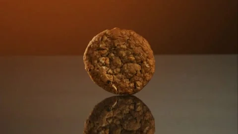 Oatmeal cookie rolling and bouncing on a reflective surface Stock Footage 327788864