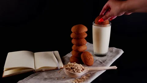 Oatmeal cookies laid out in a stack, a woman's hand soaks cookies in a milk Stock Footage 204810511