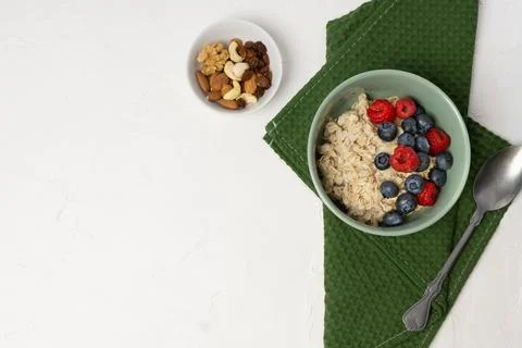 Oatmeal with fresh berry fruits. Oat porridge in a bowl with spoon and Stock Photos