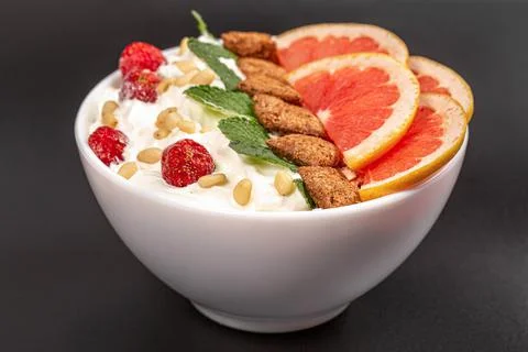 Oatmeal with pine nuts and grapefruit pieces in a bowl on a black background Stock Photos