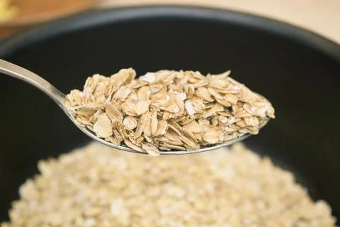 Oatmeal on a spoon close-up. Preparing breakfast in the kitchen. Cooking Stock Photos
