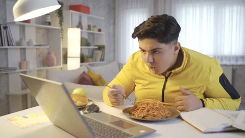 Obese boy eats pasta while watching video. Stock Footage 218970964