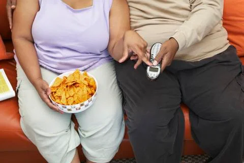 Obese Couple Sitting On Couch Stock Photos