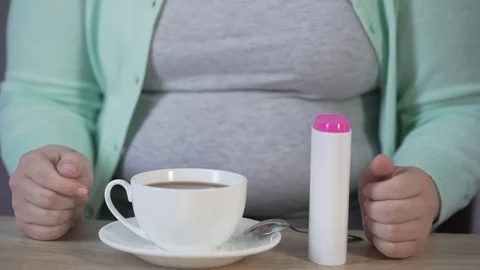 Obese lady replacing sugar on sweetener and putting into the tea, diabetes Stock Footage