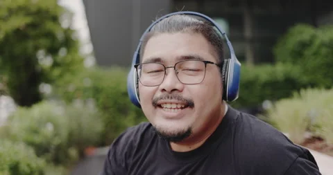Obese man wearing headphone to work and video call with laptop meetings outside  Stock Footage 159724066