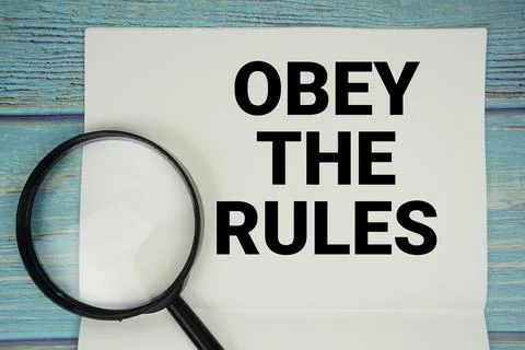Obey The Rules text written on notepad with magnifying glass flat lay on wo.. 스톡 사진