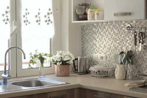 Objects and flowers, kitchen workspace with mosaic tile wall. Traditional Stock Photos