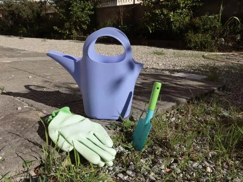 Objects and tools for gardening on sunny day. Watering can, shovel and gloves Stock Photos