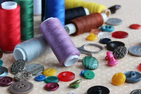 Objects for needlework: plastic buttons, colored thread and scissors Stock Photos