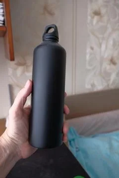 Objects in a persons hand: a flask, pens and pencils Stock Photos