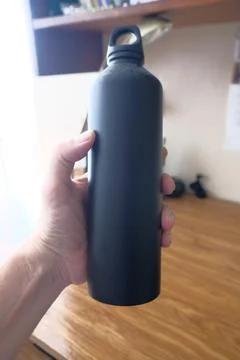 Objects in a persons hand: a flask, pens and pencils Stock Photos