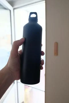 Objects in a persons hand: a flask, pens and pencils Stock Photos