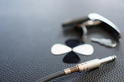 Objects to play guitar on leather surface, guitar plectrum, jack cable Stock Photos
