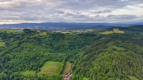 Oblique aerial panorama of mixed forest, rolling pastures, and distant ridge Stock Footage 342359366