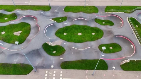 Oblique drone view of an empty pump track with sweeping berms, arrow-marked 스톡 동영상 346310968