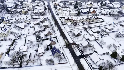 Oblique drone view over a snow-covered suburb with a main road and moving Vídeos de archivo 328063642