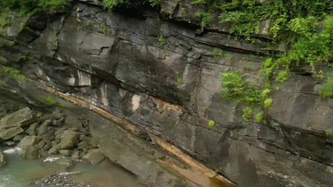 Oblique pass over a tilted rock wall beside a Philippine river, with layered Stock Footage 319471833