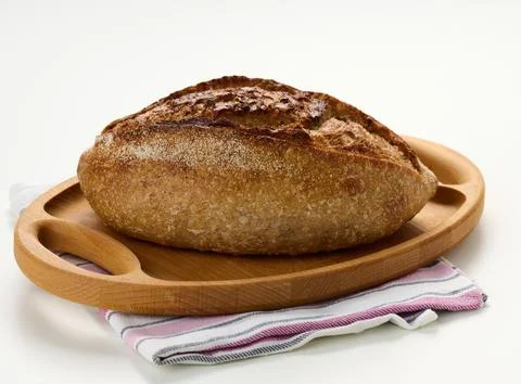 Oblong baked bread made from white wheat flour on a white table, crispy bun Stock Photos