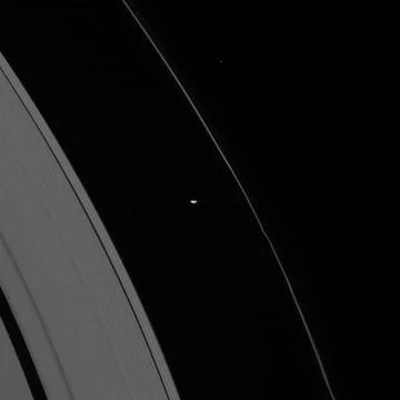 The oblong form of Prometheus glides by, trailing behind it wiggles in Sat... Fotos de archivo