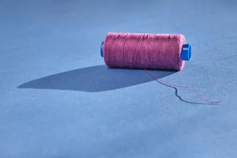 An oblong spool of sewing thread of a beautiful purple color lies with unwoun Stock Photos