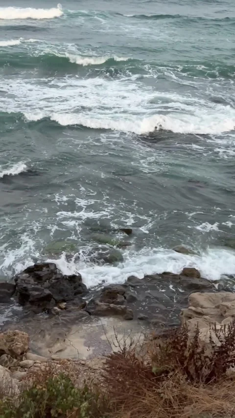 Observe the spectacular clash of powerful ocean waves against a rugged rock.. Stock Footage 316923195