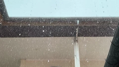 Observing rain falling on a building exterior with droplets in motion Stock Footage 325292300