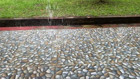 Observing Rain Water Droplets Falling onto a Pebble Tile Path in a Park Setti Stock Footage 325292278