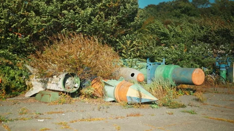 Obsolete, abandoned, and rusty combat missiles and shells stand amidst the .. Stock Footage 345584703