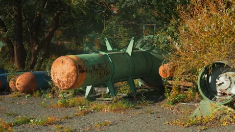 Obsolete, abandoned, and rusty combat missiles and shells stand amidst the .. Stock Footage 345590852