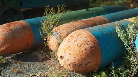 Obsolete, abandoned, and rusty combat missiles and shells stand amidst the .. Stock Footage 345591727