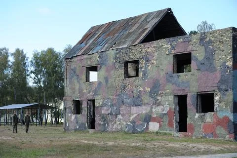 An obstacle course built like an abounded building, soldiers standing aside. Stock Photos